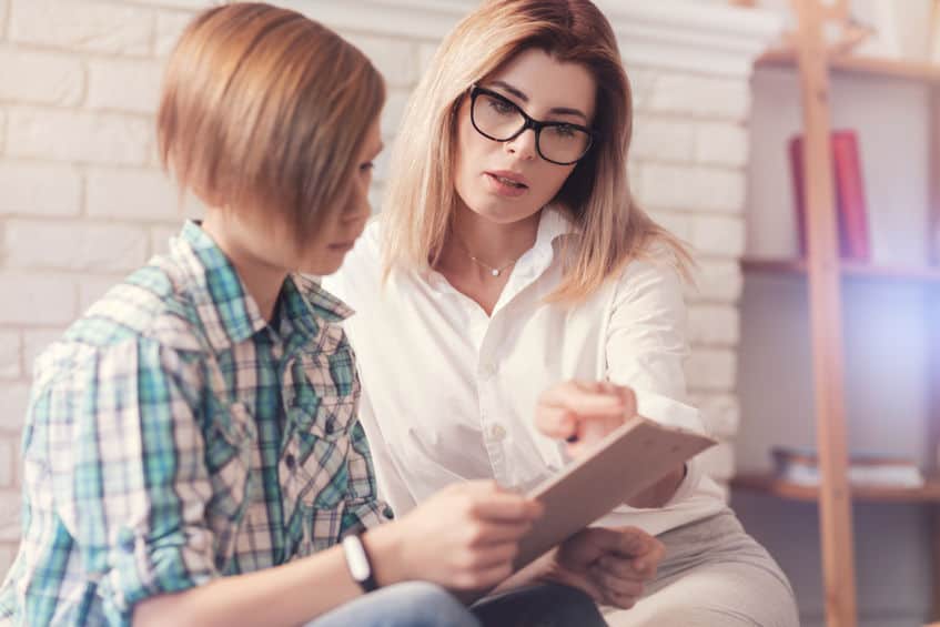 Professionelle Psychologin führt einen Test mit einem Schuljungen durch.